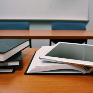 Books and a tablet on a desk in a classroom, depicting modern education.