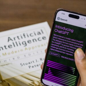 Close-up of a smartphone displaying ChatGPT app held over AI textbook.